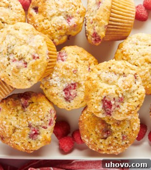 Overhead view of freshly baked raspberry oat muffins stacked on a tray, highlighting their golden tops.