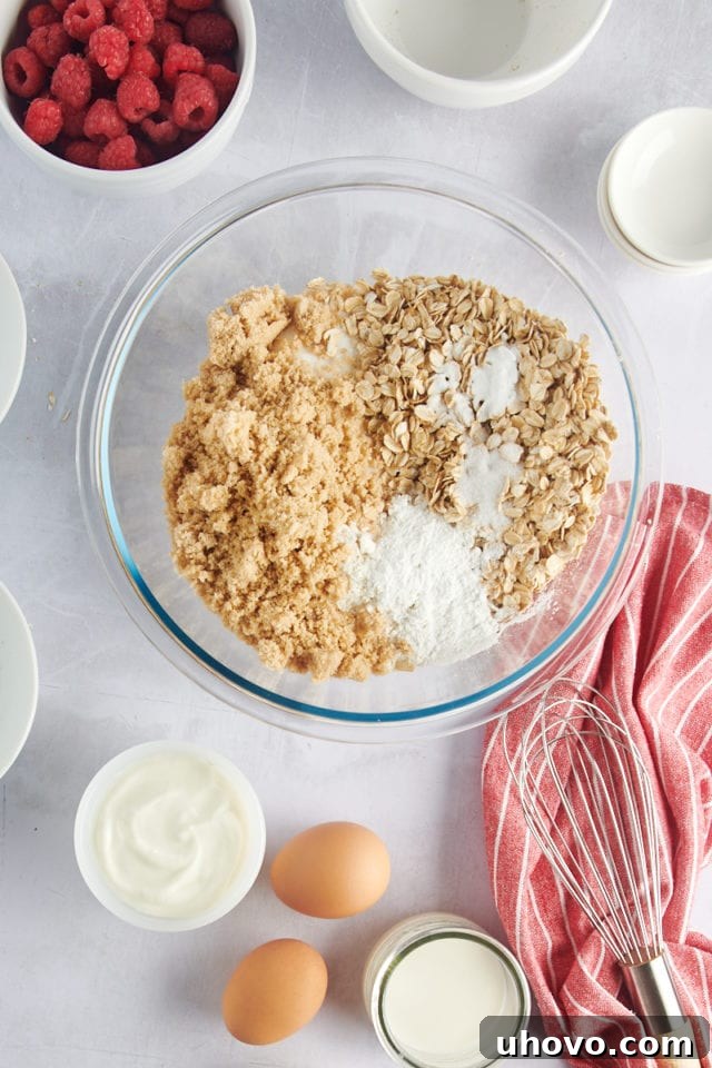 Overhead view of dry ingredients (flour, oats, baking powder, baking soda, salt) in a bowl before whisking.