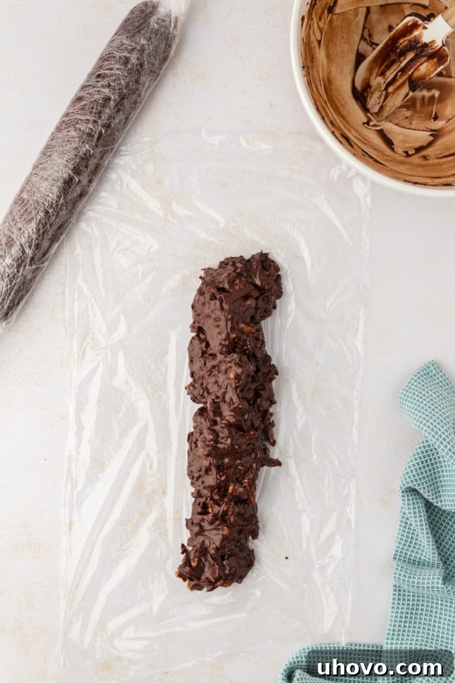An overhead view of the soft double chocolate cookie dough being carefully placed onto a sheet of plastic wrap, ready for shaping.