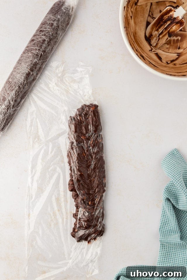 The process of shaping the double chocolate cookie dough: an overhead view shows it being rolled into a neat log within plastic wrap.