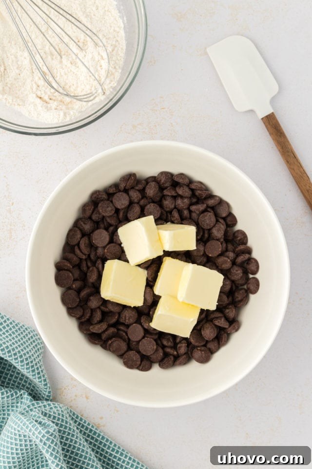An inviting overhead view of butter and bittersweet chocolate chips nestled together in a heatproof bowl, awaiting their transformation.