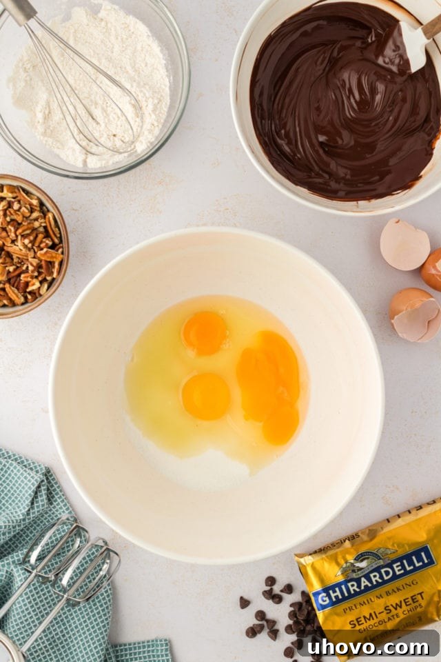 An overhead view capturing three large eggs and granulated sugar in a spacious mixing bowl, the beginning of the wet ingredients for our cookies.