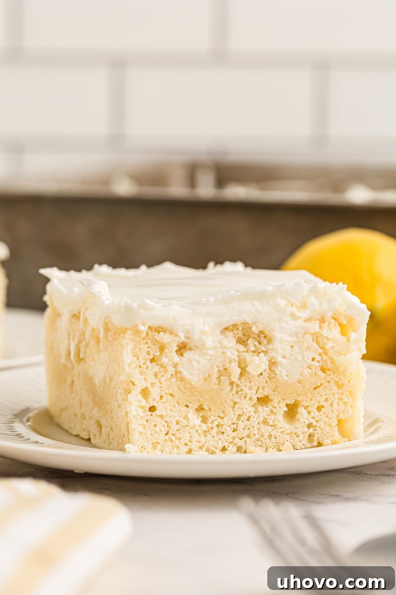 A delectable slice of lemon poke cake on a plate, showcasing its light, airy texture and generous filling, hinting at its irresistible moisture and bright citrus notes.