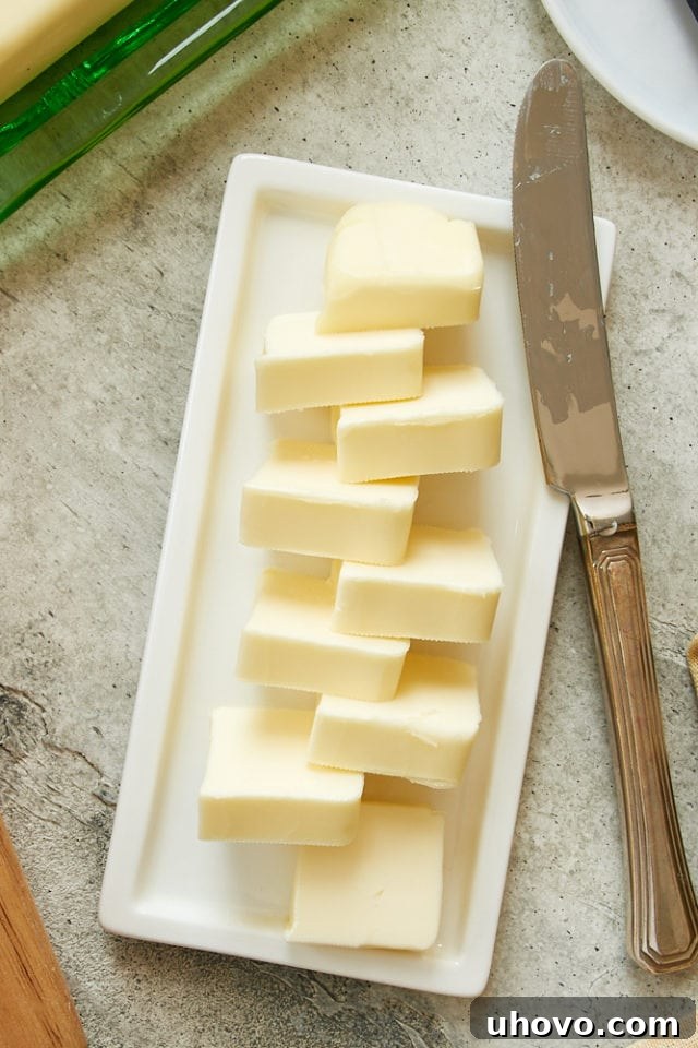 Overhead view of perfectly softened butter on a white plate, ready for creaming