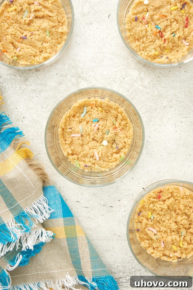 A close-up view of cookie crumbs pressed into the bottoms of small serving glasses, forming the cheesecake crust.