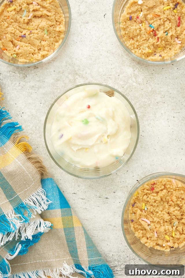 Creamy cheesecake filling being carefully spooned into a small glass over the cookie crust.
