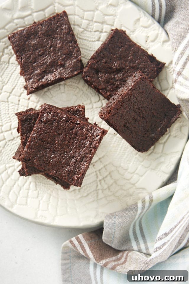 Overhead view of perfectly stacked small batch brownies on a white plate, showcasing their rich, dark color.
