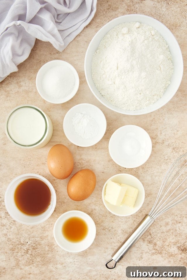 A selection of essential ingredients for Easy Pancake Muffins laid out, including flour, sugar, fresh eggs, golden maple syrup, and unsalted butter. These are simple staples you likely already have for a homemade breakfast treat.