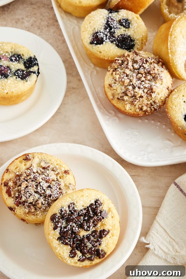 An arrangement of fresh, fluffy Pancake Muffins on white plates and a matching serving tray, enticingly garnished and ready for a delicious breakfast or brunch spread.