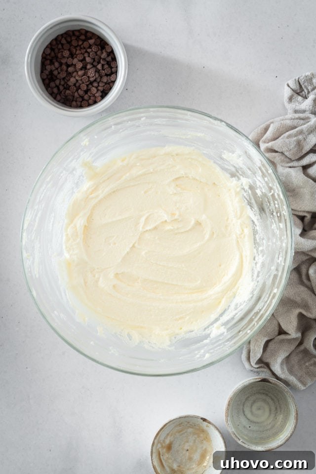An overhead shot of homemade buttercream in a glass bowl, showcasing its smooth and fluffy consistency, ready for frosting.