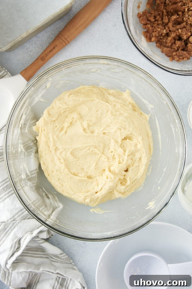 A luscious, smooth coffee cake batter, enriched with sour cream, waiting in a glass mixing bowl to be transferred to the pan.