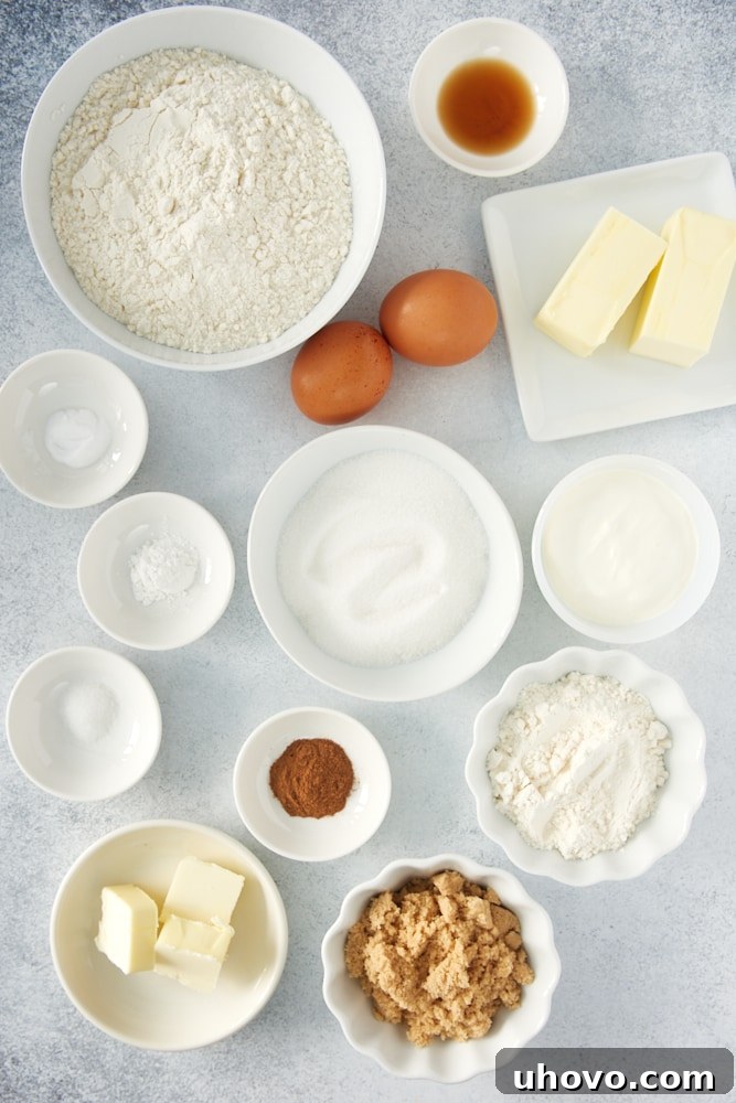 A collection of essential ingredients for making coffee cake, including neatly stacked bags of flour and sugar, a stick of butter, fresh eggs, and a small bowl of fragrant cinnamon, all laid out on a clean surface.