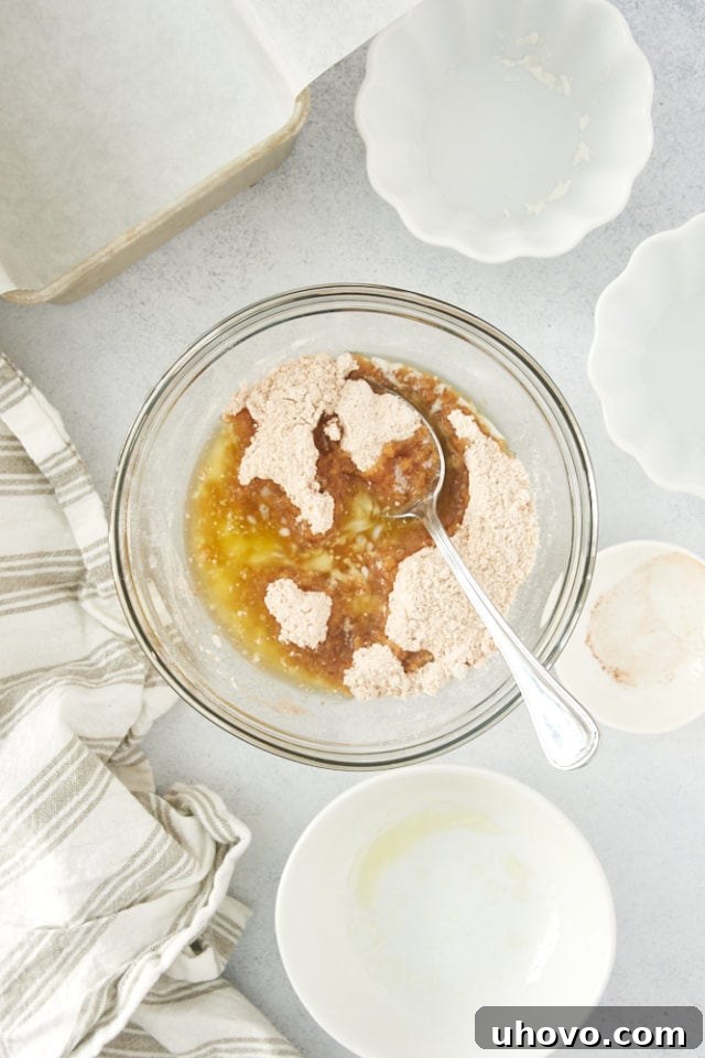 Melted butter being poured into a bowl containing brown sugar, flour, and cinnamon, initiating the creation of the crumb topping.