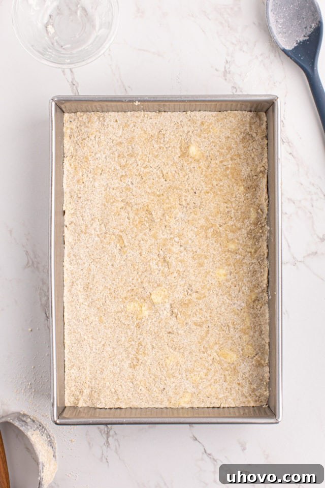 Overhead view of shortbread crust evenly pressed into a baking pan, ready for baking.