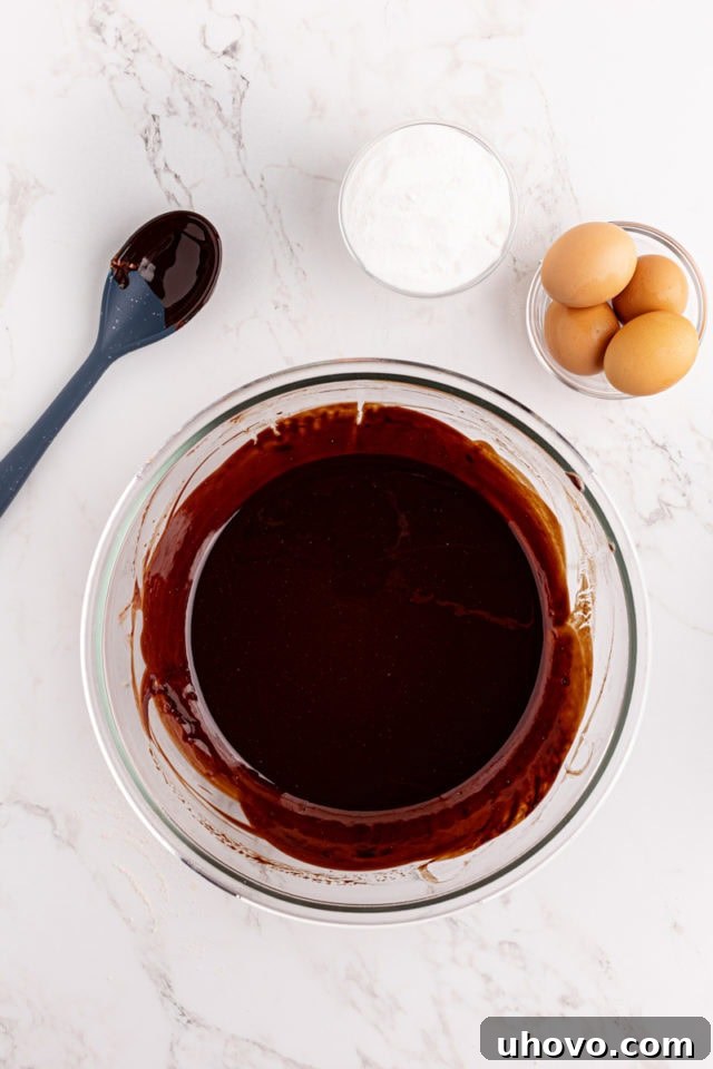 Overhead view of melted butter and chopped bittersweet chocolate in a heatproof bowl.