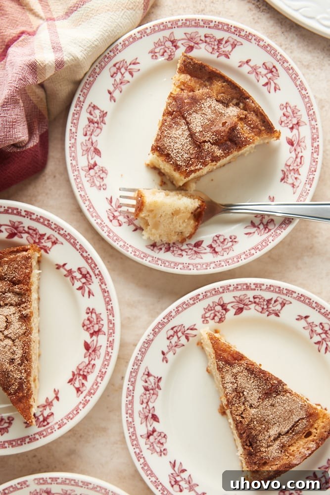 Multiple slices of Cinnamon Pear Cake are presented on individual red floral-rimmed white plates, highlighting the elegant presentation and inviting appeal of this dessert.