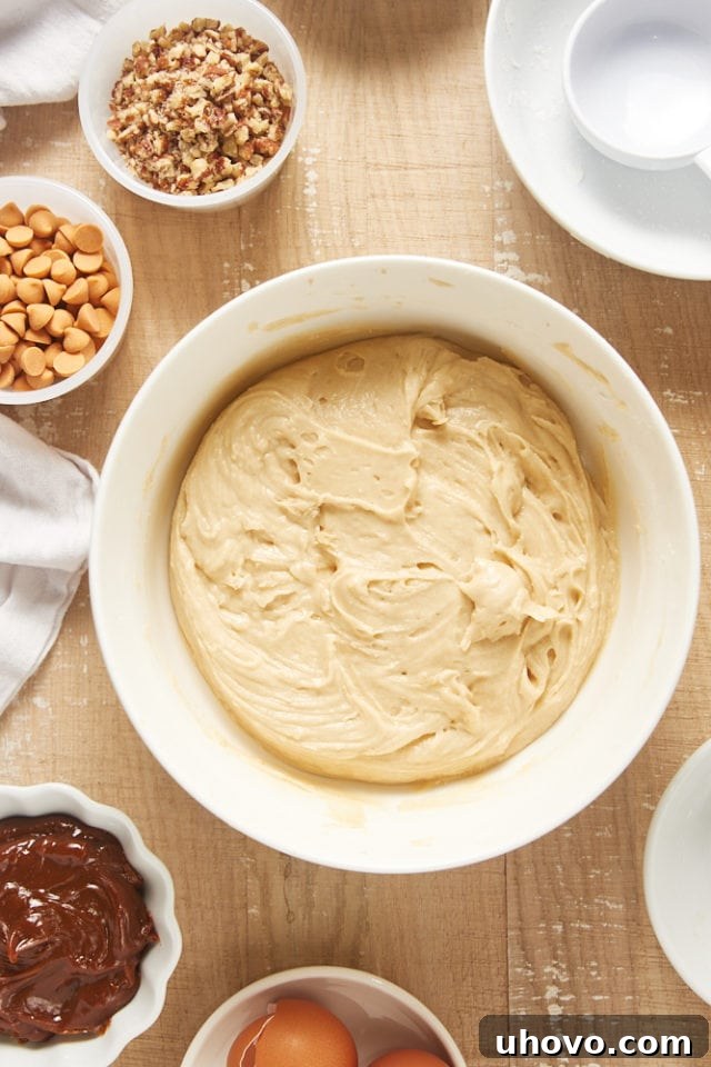 Overhead view of perfectly mixed brown sugar snack cake batter in a white mixing bowl, smooth and ready for additions.
