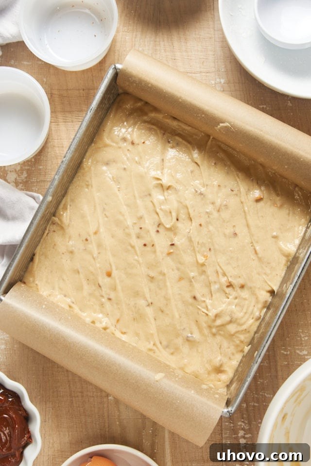 Overhead view of the Brown Sugar Snack Cake batter evenly spread in a parchment-lined baking pan, ready for the oven.