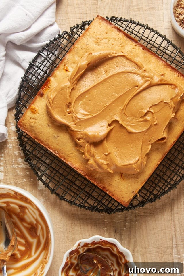 Overhead view of decadent dulce de leche frosting being spread onto a cooled brown sugar cake with an offset spatula.