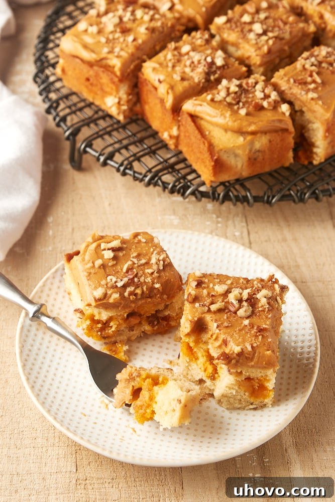 A perfectly portioned slice of Brown Sugar Snack Cake with creamy Dulce de Leche Frosting on a white and beige plate.