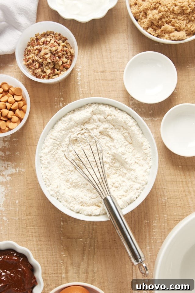 Overhead view of dry ingredients (flour, baking powder, salt) perfectly mixed in a white mixing bowl.