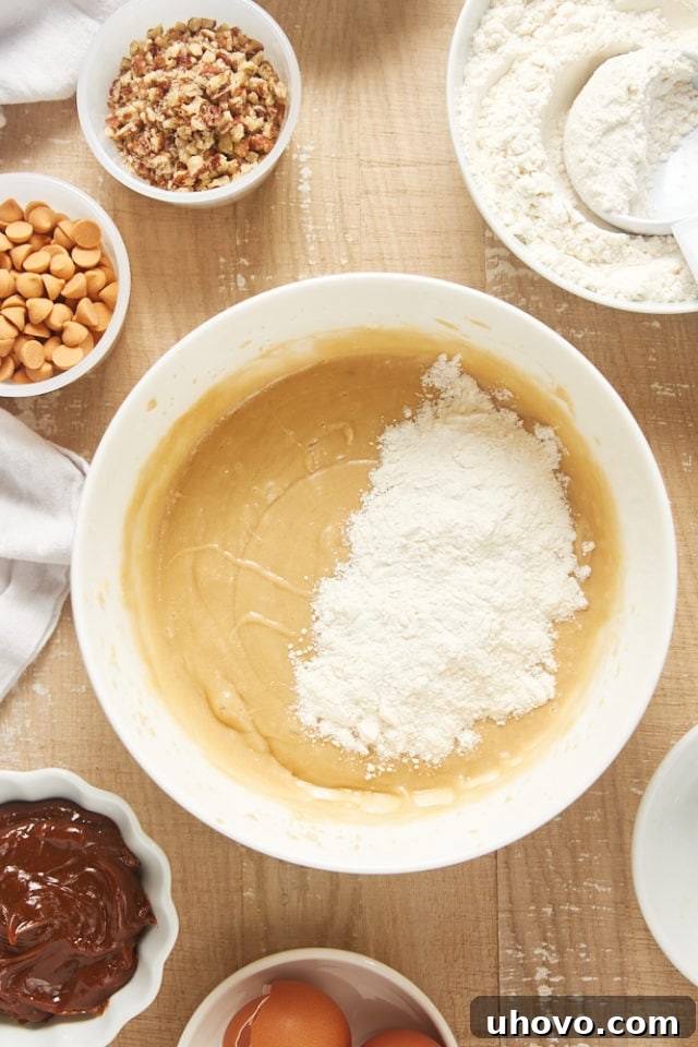 Overhead view of dry ingredients being added to the wet mixture for the brown sugar cake, demonstrating proper mixing technique.
