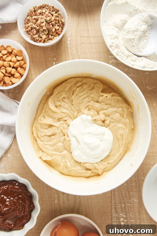 Overhead view of sour cream being carefully folded into the brown sugar cake batter, adding moisture and tang.