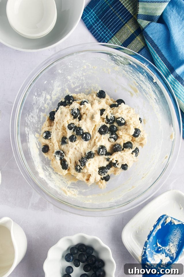 Overhead view of the completed blueberry biscuit dough in a glass mixing bowl, ready for scooping.
