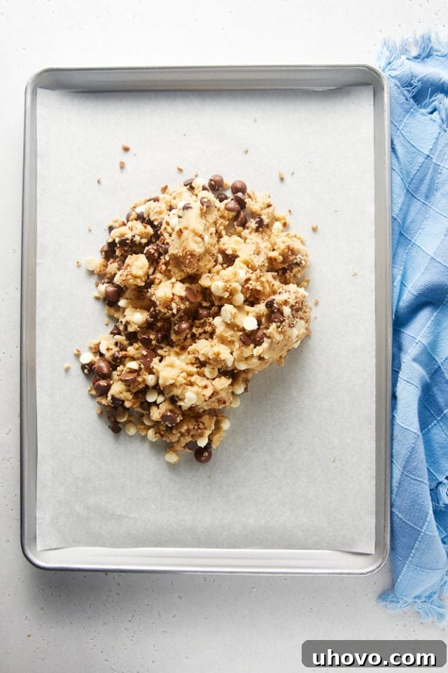 Overhead view of the prepared Triple Chocolate Chip Cookie Brittle dough transferred to a parchment-lined baking sheet.