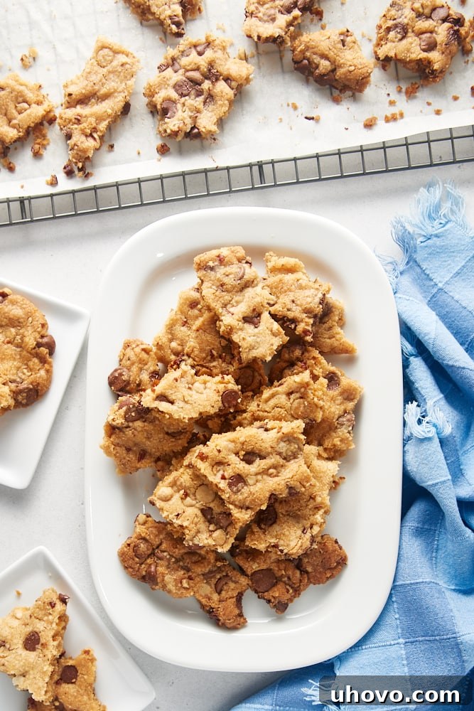 An array of Triple Chocolate Chip Cookie Brittle displayed on a white tray, plates, and a cooling rack, showcasing its versatility in presentation.