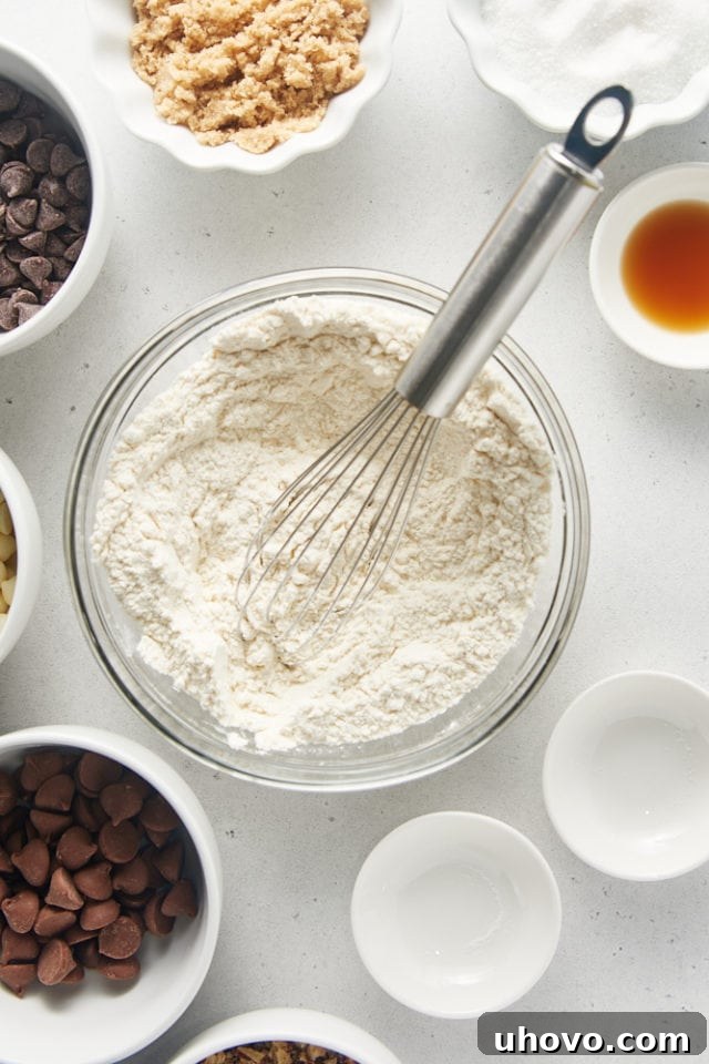 Overhead view of dry ingredients (flour, baking soda, salt) perfectly mixed in a clear glass mixing bowl.
