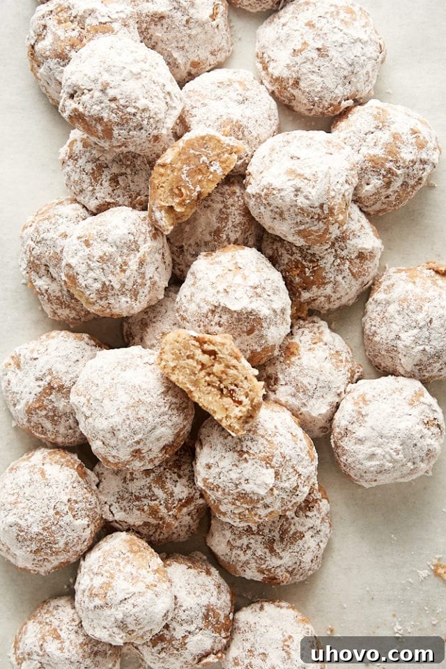 A generous pile of freshly baked Nutty Spiced Snowdrop Cookies, dusted with their signature spiced confectioners' sugar coating, presented invitingly.