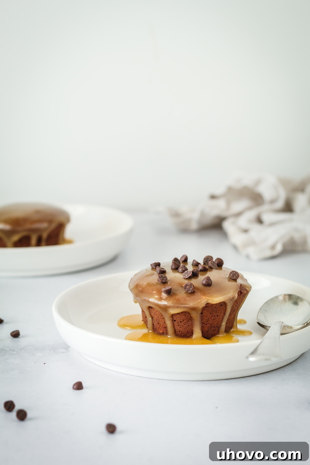 Two mini pound cakes on white plates, topped with chocolate chips
