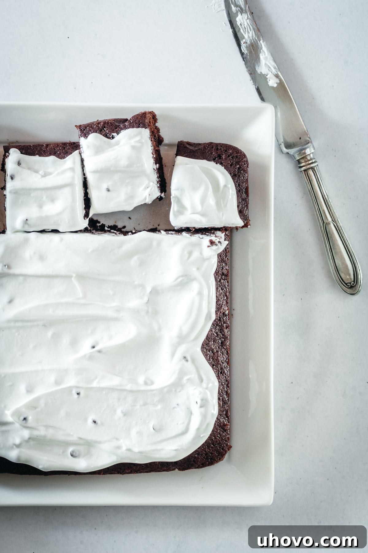 Overhead view of brownies being cut into squares on platter