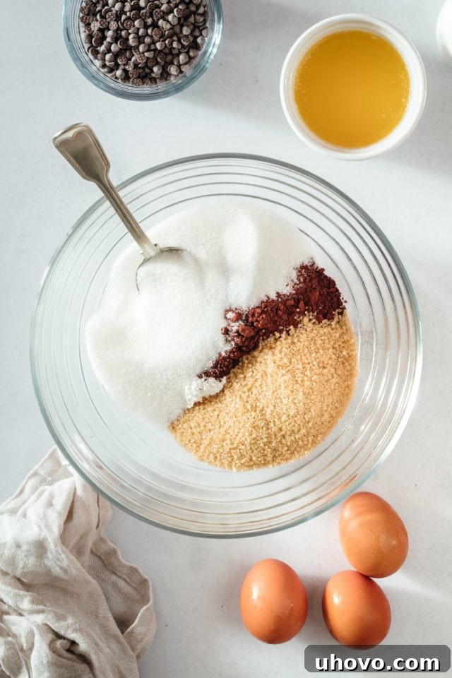 Overhead view of dry brownie ingredients in glass mixing bowl before stirring