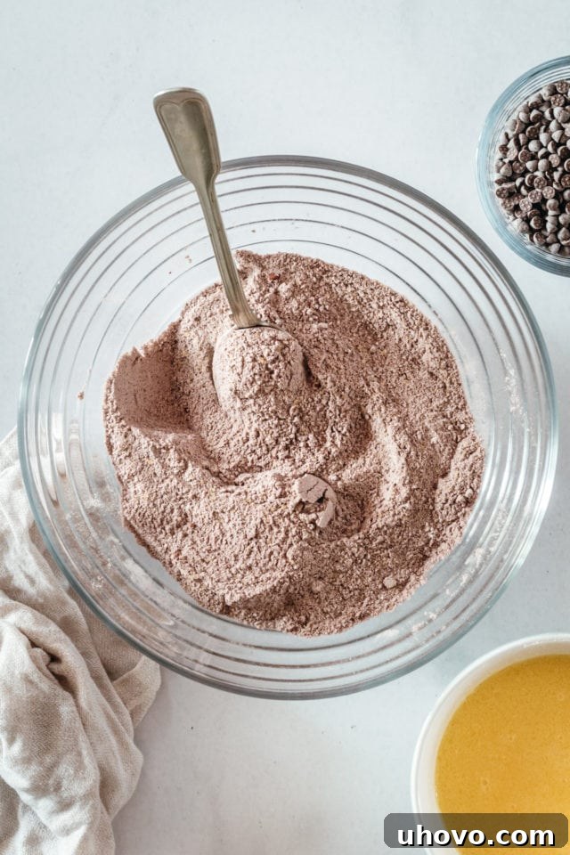Overhead view of dry brownie ingredients in glass bowl with spoon