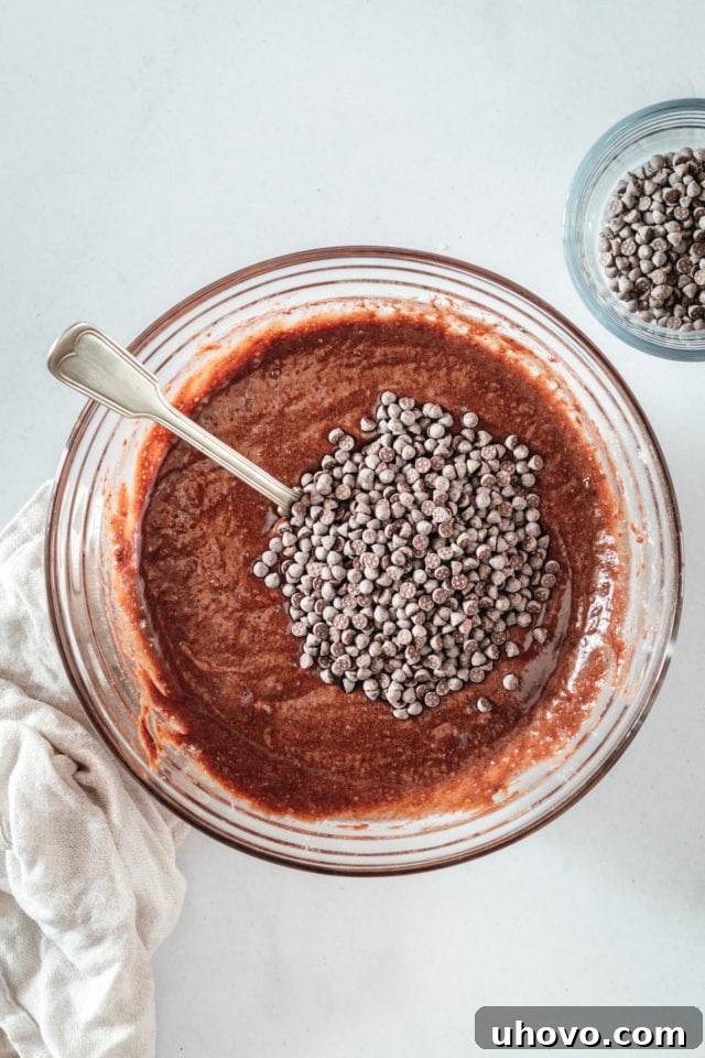 Overhead view of chocolate chips being stirred into brownie batter