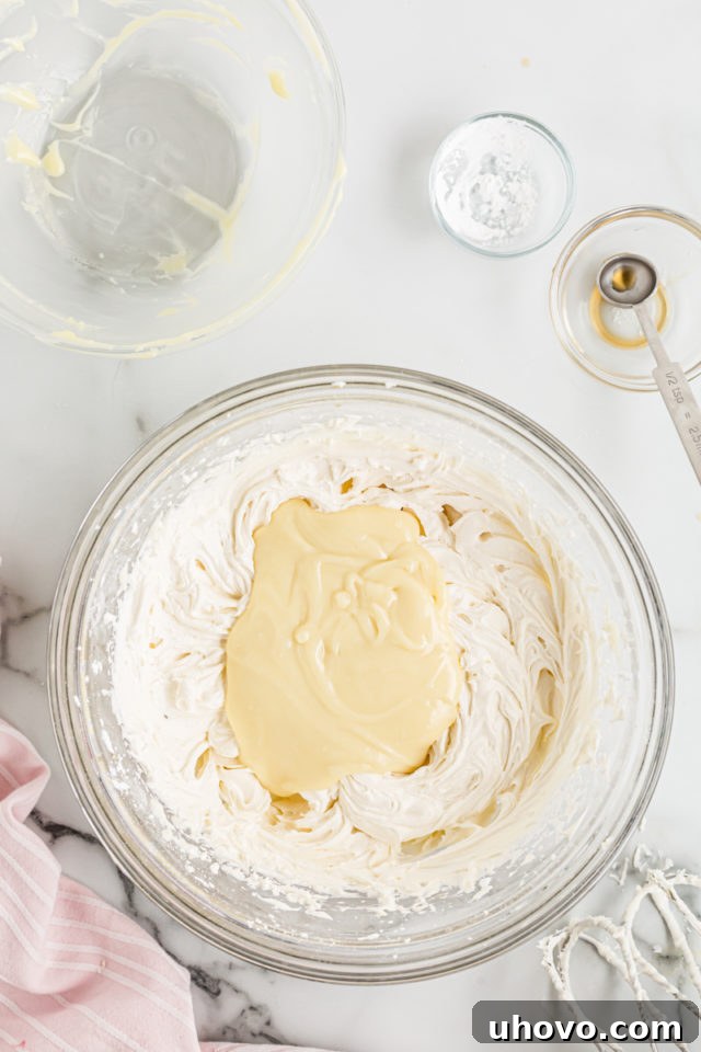 Adding the melted white chocolate mixture to the frosting base