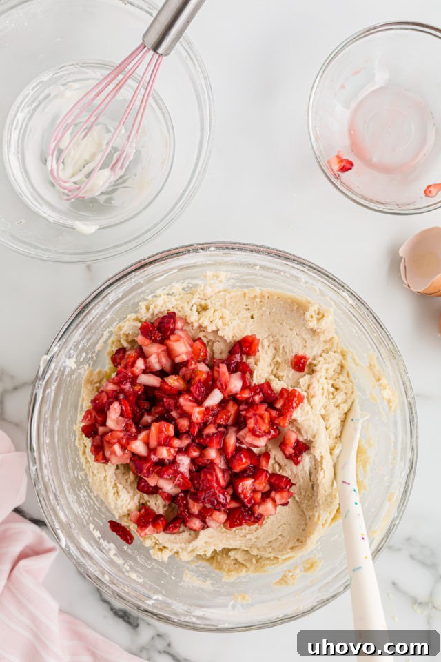 Folding fresh strawberries into the cupcake batter