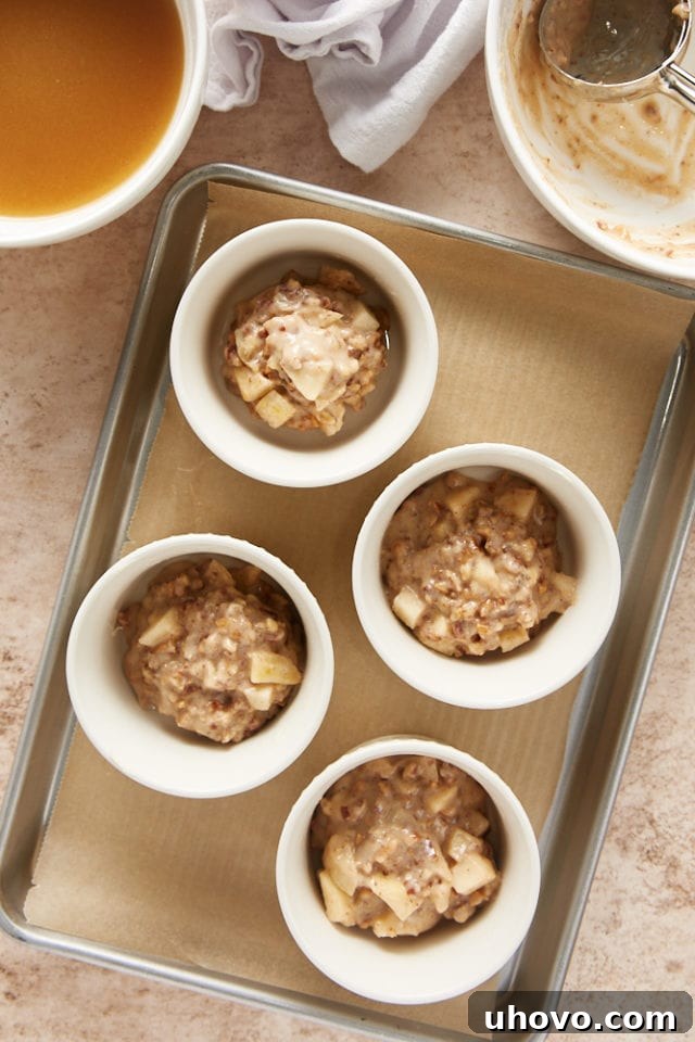 overhead view of pudding cake batter in white ramekins on a parchment-lined baking sheet