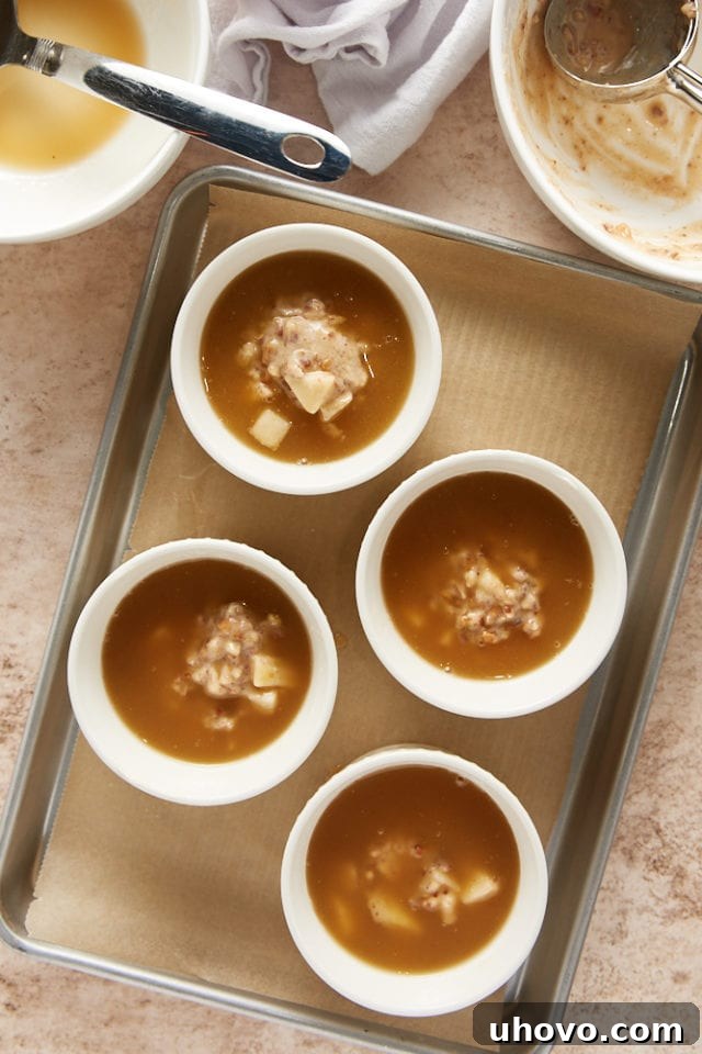 overhead view of pudding mixture added to cake batter in white ramekins on a parchment-lined baking sheet