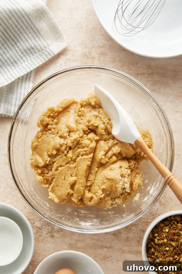The cookie dough, with its rich, mixed consistency, rests in a glass mixing bowl, showing minimal streaks of flour.