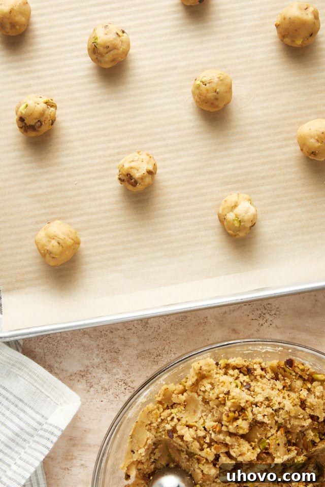 Unbaked Brown Butter Pistachio cookie dough balls neatly arranged on a parchment-lined baking sheet, ready to go into the oven.