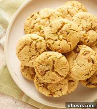 overhead view of Brown Butter Pistachio Cookies piled on a beige plate