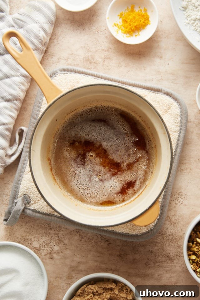 Close-up overhead view of butter browning in a saucepan, showing the golden liquid and developing brown specks.