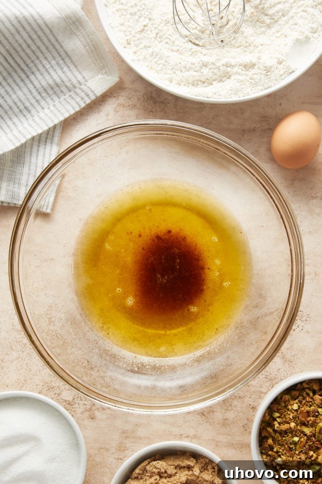 Overhead view of perfectly browned butter, with all its rich brown solids, transferred into a clear glass mixing bowl, ready for the next step.