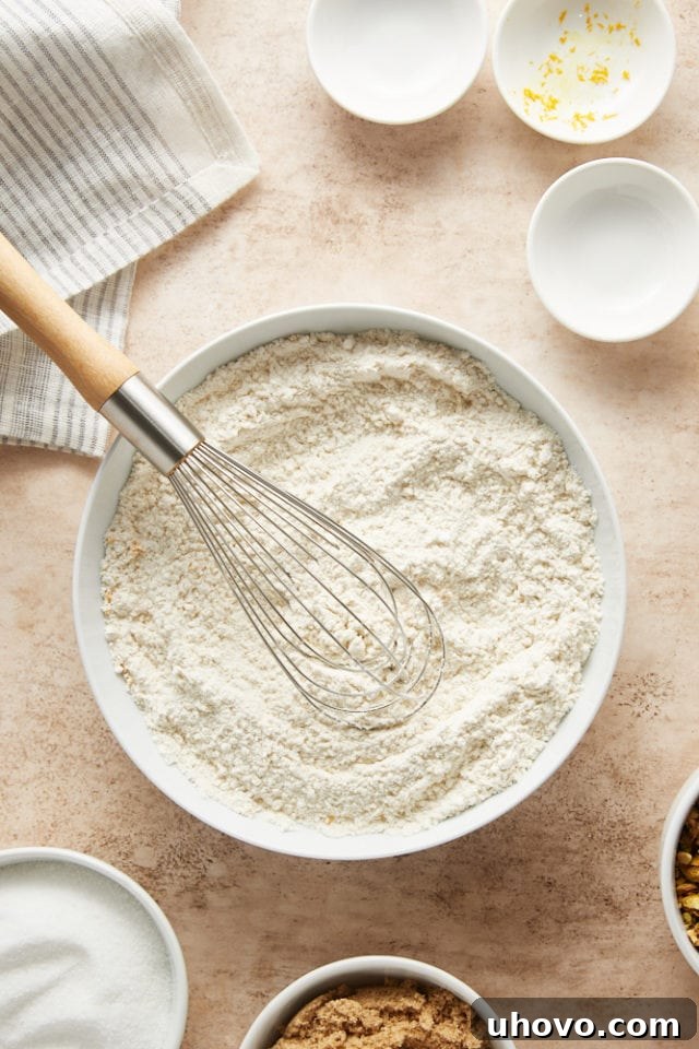 The dry ingredients for the cookies – flour, baking soda, salt, and orange zest – are neatly whisked together in a bowl.