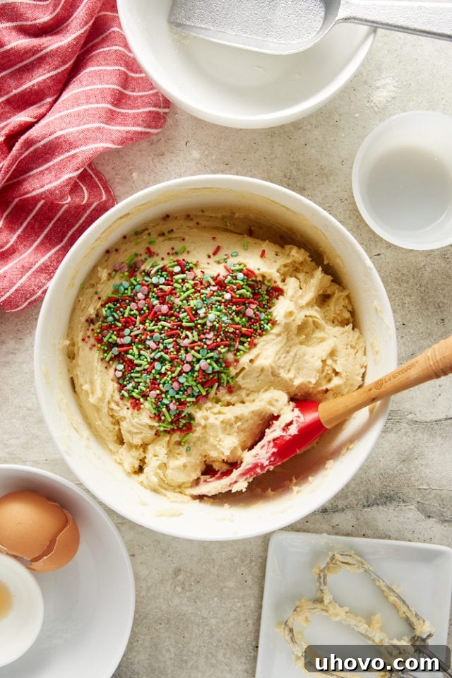 Overhead view of sprinkles being added to the prepared sugar cookie dough.
