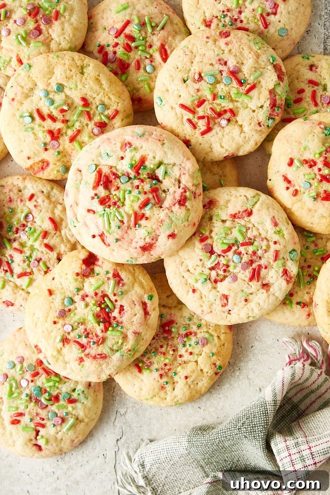 Overhead view of soft Christmas sugar cookies artfully scattered across a light gray surface, invitingly displayed.