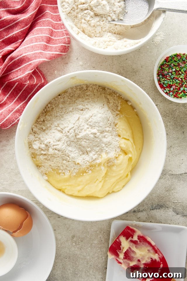Overhead view of the flour mixture being gradually added to the wet ingredients in a mixing bowl.